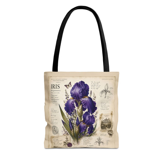 A canvas tote bag with black shoulder straps, featuring a vintage-style botanical print of purple irises on a cream background with handwritten text and illustrations.