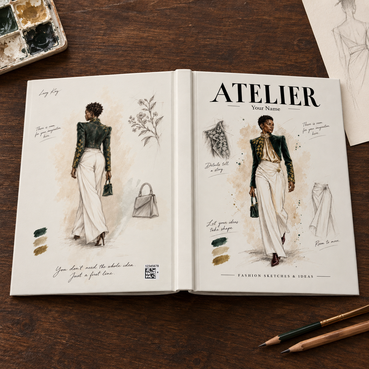An open fashion sketchbook on a dark wooden desk, showing illustrated outfit designs, handwritten notes, color swatches, and the title 'ATELIER'. A paint palette, pencils, and another sketch sheet are visible around it.